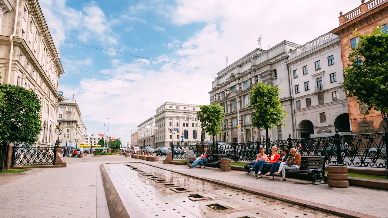 People resting, sitting on bench on Lenin Street in summer in Mi