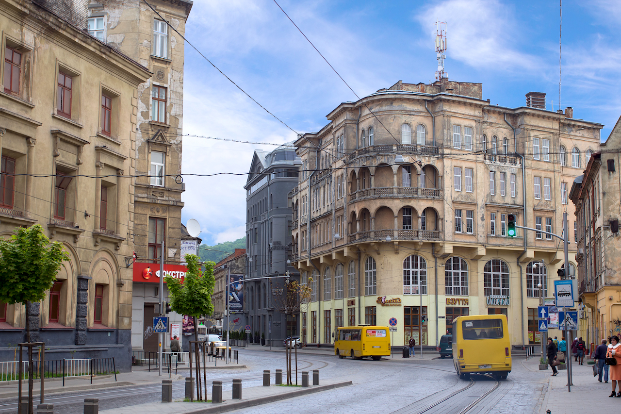 LVIV UKRAINE - MAY 8 2016: One of the streets of Lviv in the afternoon: shuttle buses on the road people waiting for transport and old-style buildings Ukraine