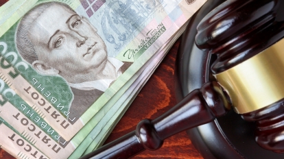 Gavel and Ukrainian hryvnias on a wooden table