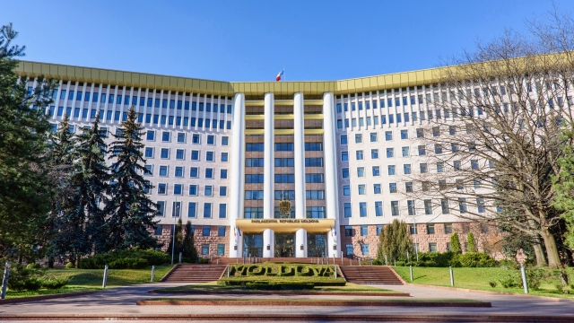 Parliament of the republic of moldova in chisinau, national flag, stefan cel mare street, spring time with blue sky
