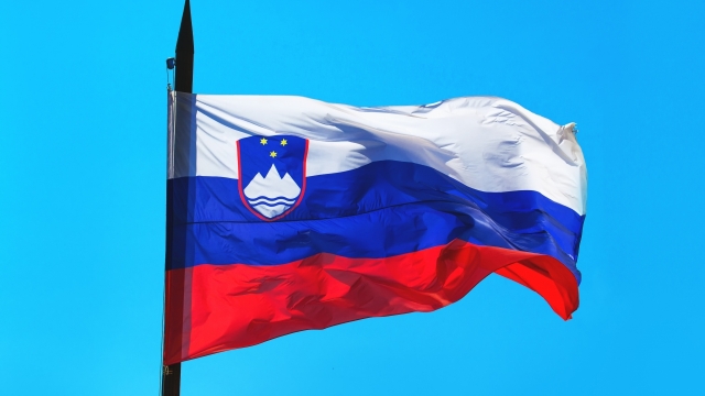 Slovenia flag against blue sky waving in wind