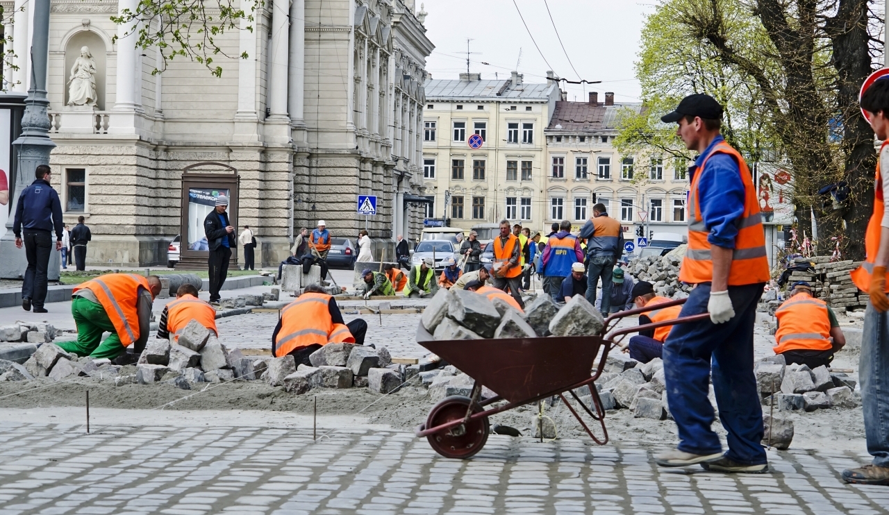 LVOV UKRAINE - APRIL 25: Workers masons laid paving stones in the repair of the main street on April 25 2013 in Lviv Ukraine