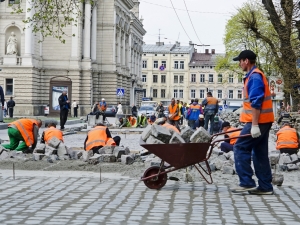 LVOV UKRAINE - APRIL 25: Workers masons laid paving stones in the repair of the main street on April 25 2013 in Lviv Ukraine