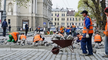 LVOV UKRAINE - APRIL 25: Workers masons laid paving stones in the repair of the main street on April 25 2013 in Lviv Ukraine