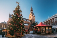 Christmas Market On The Dome Square With Riga Dome Cathedral In Riga, Latvia. Christmas Tree And Trading Houses With Sale Of Christmas Gifts, Sweets And Mulled Wine. Famous Landmark.