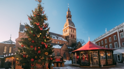 Christmas Market On The Dome Square With Riga Dome Cathedral In Riga, Latvia. Christmas Tree And Trading Houses With Sale Of Christmas Gifts, Sweets And Mulled Wine. Famous Landmark.