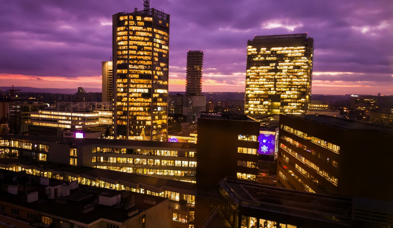 Prague skyscrapers in blue hour with purple sky. Modern building architecture after sunset. Office center in capital city. Czech republic lighting buildings.