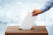 Ballot box with person casting vote on blank voting slip