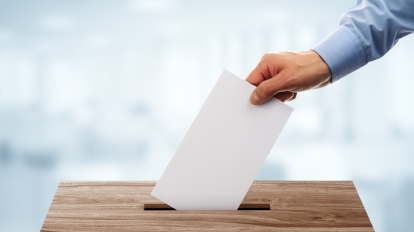 Ballot box with person casting vote on blank voting slip