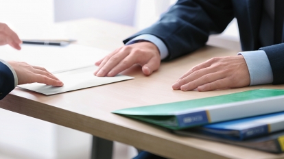 Man giving money in envelope to businessman at table. Corruption concept