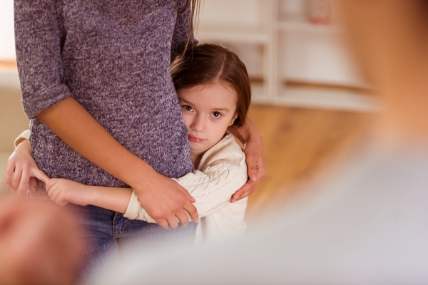 Child hugs her mother and protects her from evil father during an argument at home